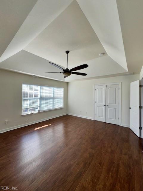 interior space featuring a closet, a raised ceiling, ceiling fan, wood finished floors, and baseboards