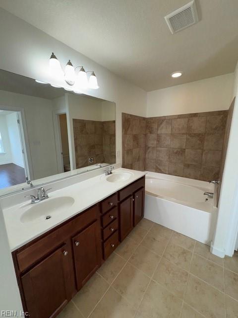 bathroom featuring double vanity, visible vents, a sink, and a bath