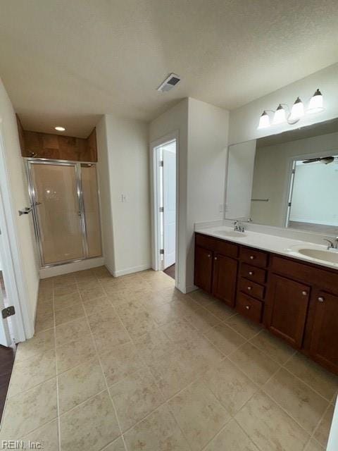 bathroom featuring baseboards, double vanity, a sink, and a shower stall