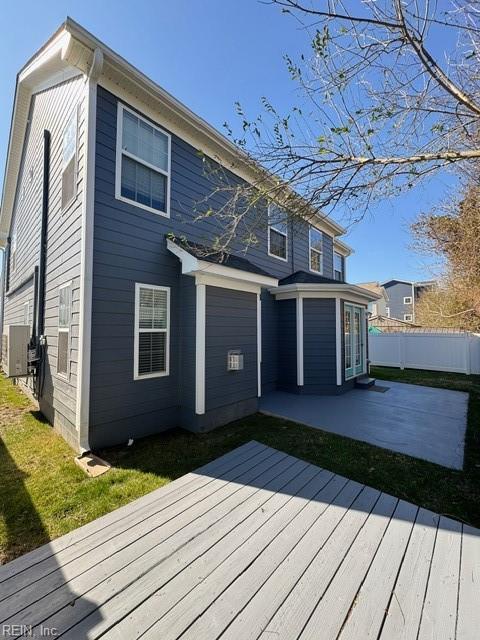 back of house with a wooden deck, fence, a lawn, and a patio