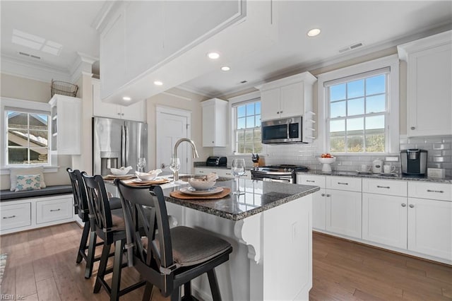 kitchen featuring wood-type flooring, appliances with stainless steel finishes, and crown molding