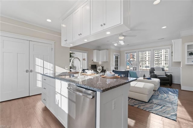 kitchen with ornamental molding, stainless steel dishwasher, dark stone counters, and white cabinetry