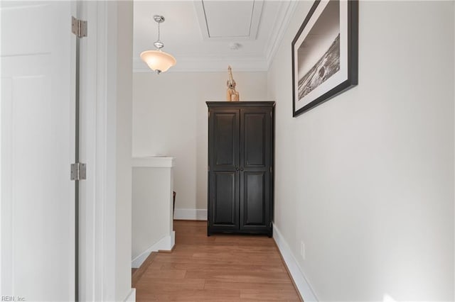 corridor featuring attic access, baseboards, crown molding, an upstairs landing, and light wood-style floors