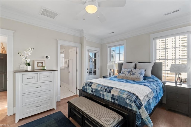 bedroom featuring ornamental molding, visible vents, and wood finished floors