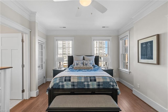 bedroom featuring baseboards, visible vents, ornamental molding, and wood finished floors