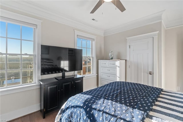 bedroom with baseboards, visible vents, a ceiling fan, ornamental molding, and wood finished floors