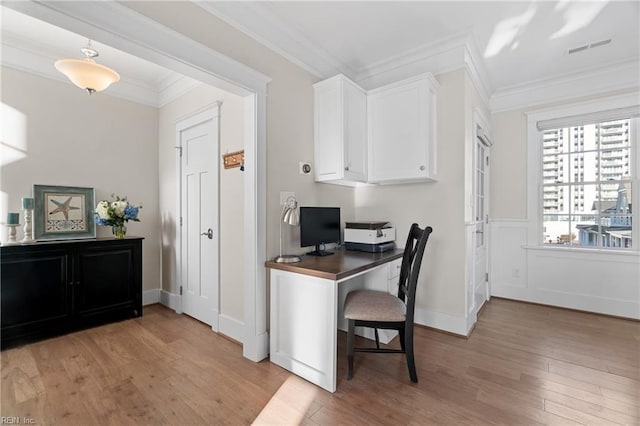 office featuring baseboards, light wood finished floors, visible vents, and crown molding