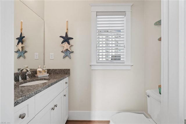 bathroom featuring toilet, baseboards, and vanity