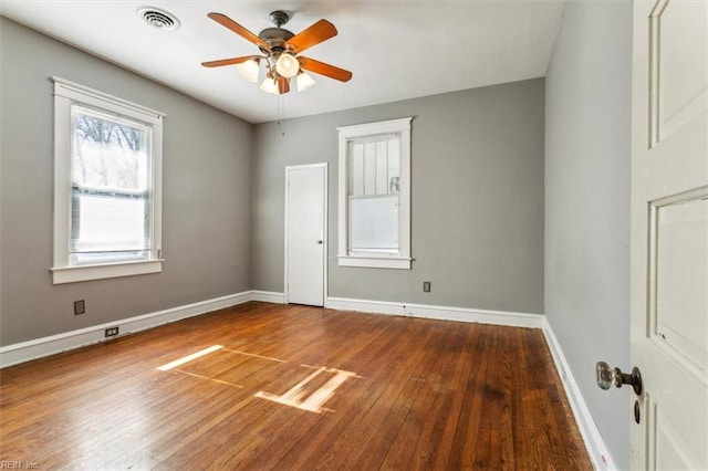 spare room featuring a ceiling fan, wood-type flooring, visible vents, and baseboards