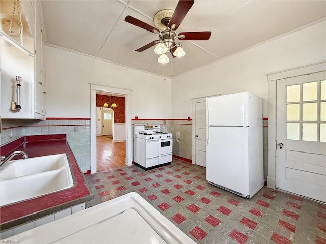 kitchen featuring white appliances, plenty of natural light, a sink, and wainscoting