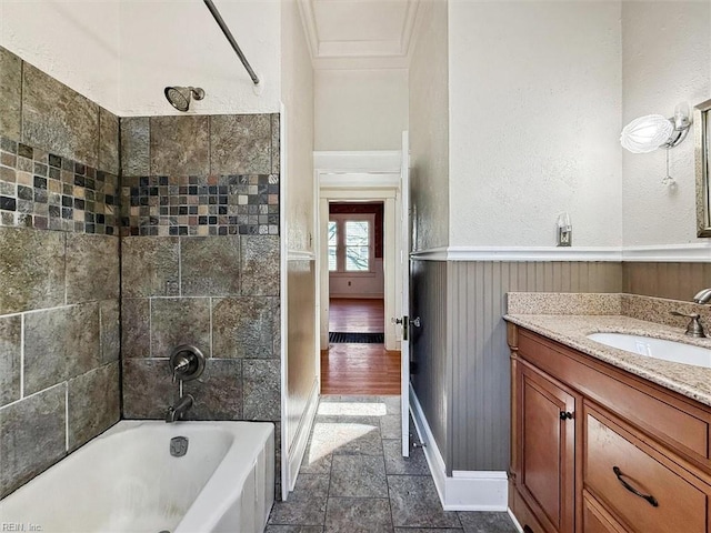 full bathroom featuring stone tile floors, shower / bathtub combination, a textured wall, vanity, and baseboards