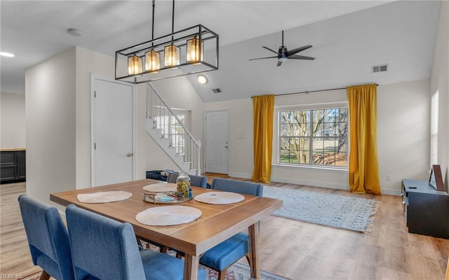 dining space with lofted ceiling, visible vents, a ceiling fan, stairway, and light wood-type flooring