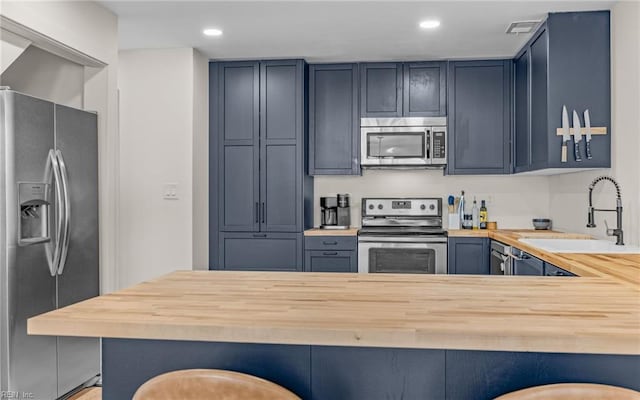 kitchen featuring wood counters, stainless steel appliances, and a sink