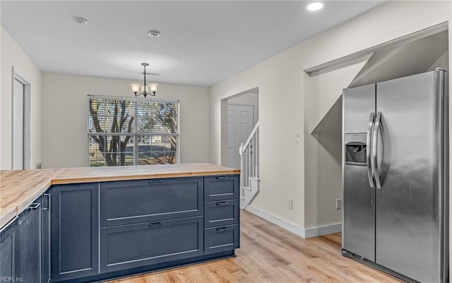 kitchen with a chandelier, stainless steel refrigerator with ice dispenser, wood counters, and light wood-style flooring