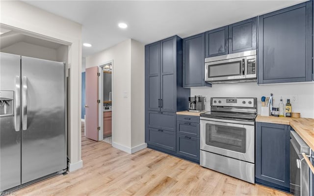 kitchen featuring stainless steel appliances, recessed lighting, blue cabinets, light wood-type flooring, and baseboards