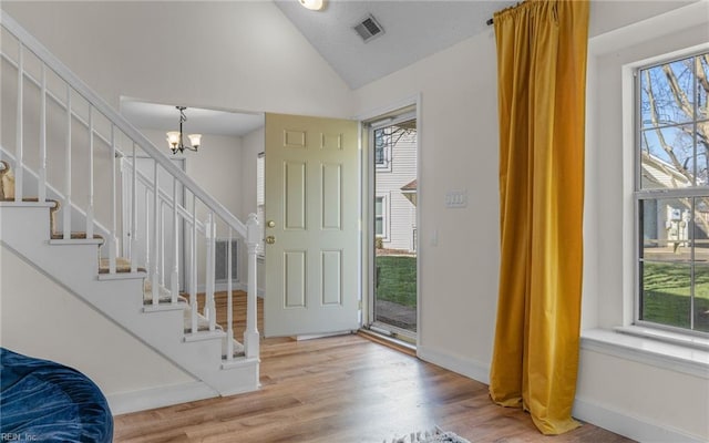 entryway with lofted ceiling, a healthy amount of sunlight, visible vents, and wood finished floors