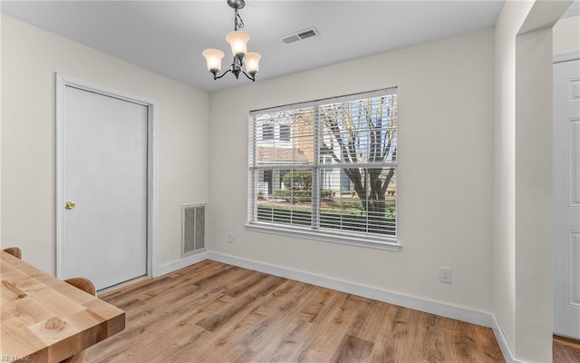 unfurnished dining area with a chandelier, visible vents, light wood-style flooring, and baseboards