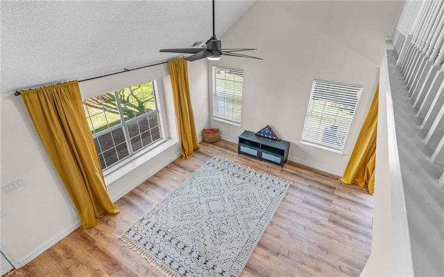 sitting room with a ceiling fan, lofted ceiling, baseboards, and wood finished floors