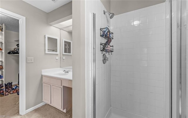 full bath with a stall shower, baseboards, a walk in closet, and vanity