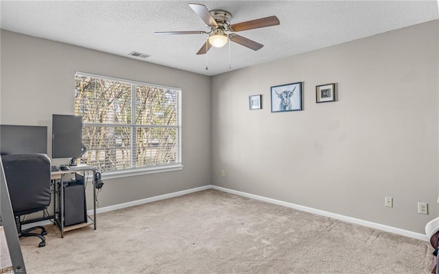 carpeted office featuring baseboards, visible vents, ceiling fan, and a textured ceiling