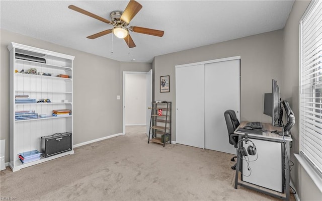 carpeted home office with a ceiling fan and baseboards