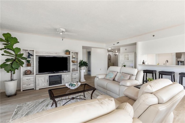 living room featuring a ceiling fan, a textured ceiling, and wood finished floors