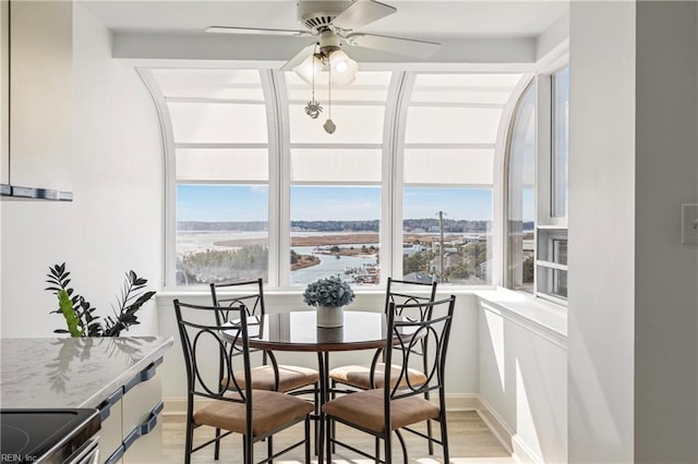 dining area featuring a ceiling fan, light wood-type flooring, and baseboards