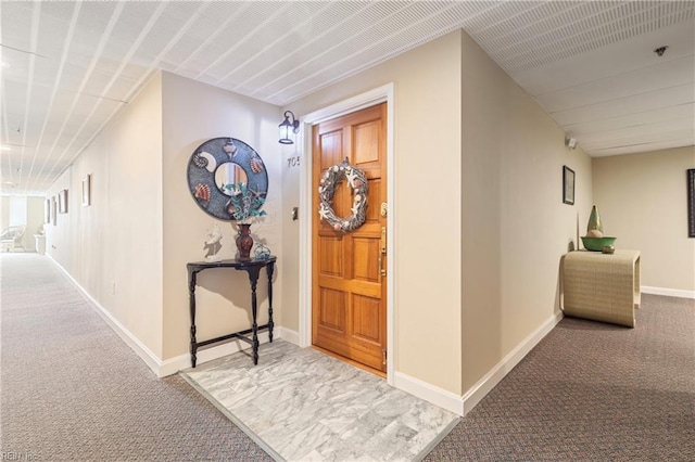 hallway featuring carpet and baseboards