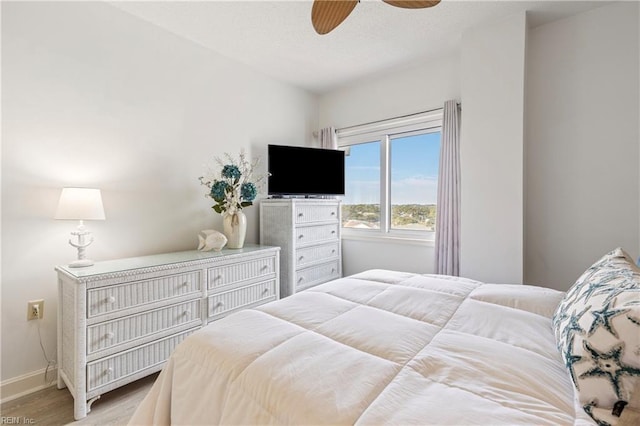 bedroom featuring a ceiling fan, baseboards, and light wood finished floors