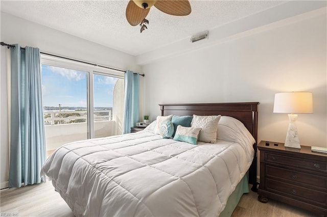 bedroom with a textured ceiling, ceiling fan, visible vents, and light wood-style floors