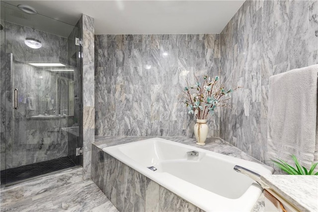 full bathroom featuring a bath, a marble finish shower, and tile walls