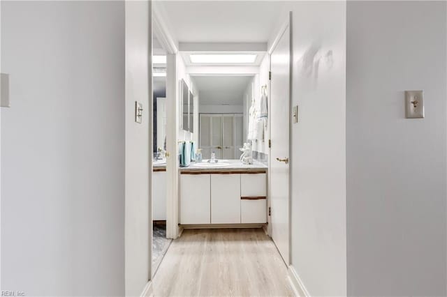 hallway with light wood finished floors and a sink