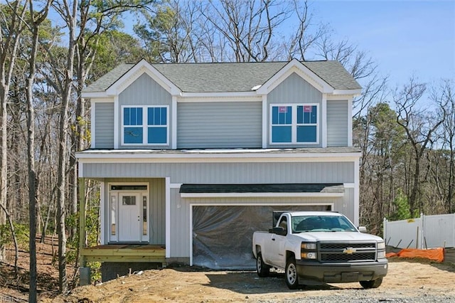 view of front of home featuring a shingled roof, fence, and dirt driveway