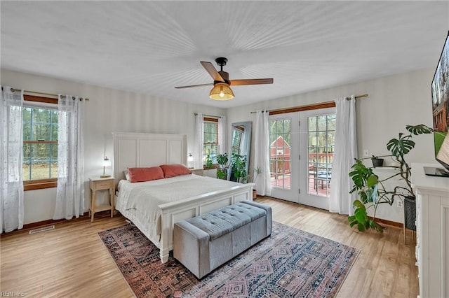 bedroom with access to outside, multiple windows, and light wood-type flooring