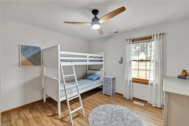 bedroom with wood finished floors, visible vents, and baseboards