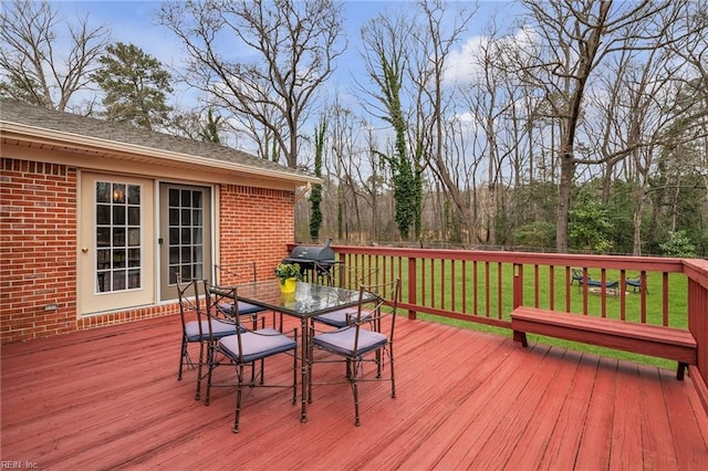 deck with outdoor dining area, a yard, and area for grilling