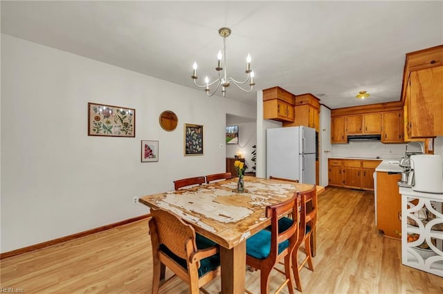 dining room featuring a chandelier, light wood finished floors, and baseboards