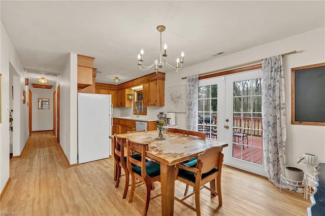 dining area with a chandelier, french doors, light wood-style flooring, and visible vents