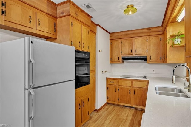 kitchen with light countertops, visible vents, a sink, black appliances, and exhaust hood