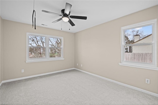 carpeted spare room featuring ceiling fan, visible vents, and baseboards