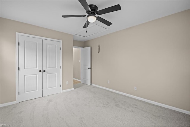 unfurnished bedroom featuring ceiling fan, carpet flooring, baseboards, a closet, and attic access