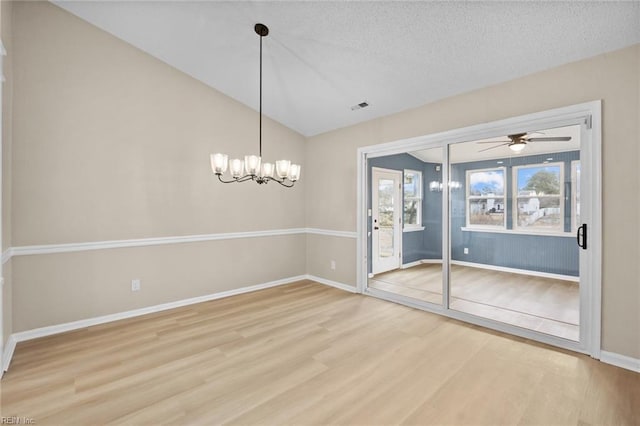 empty room with baseboards, visible vents, lofted ceiling, wood finished floors, and a textured ceiling