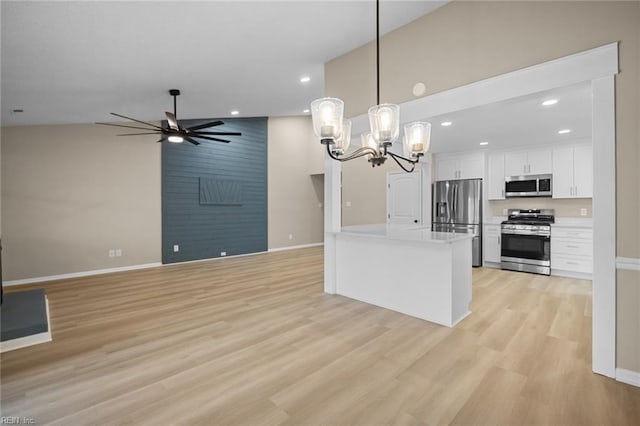 kitchen with pendant lighting, light wood finished floors, appliances with stainless steel finishes, white cabinets, and ceiling fan with notable chandelier