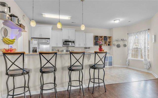 kitchen with stainless steel appliances, a breakfast bar, dark wood-type flooring, white cabinetry, and open shelves