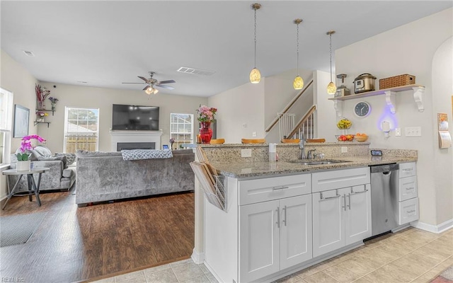 kitchen featuring a fireplace, visible vents, stainless steel dishwasher, white cabinetry, and a peninsula