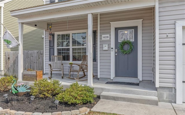 property entrance with covered porch and fence