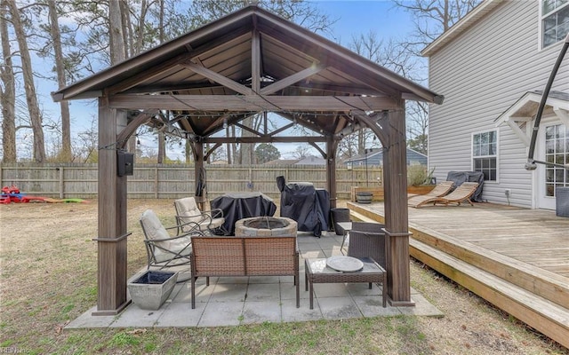 view of patio with area for grilling, a gazebo, fence, a deck, and a fire pit