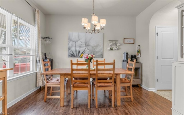 dining area with arched walkways, baseboards, wood finished floors, and an inviting chandelier