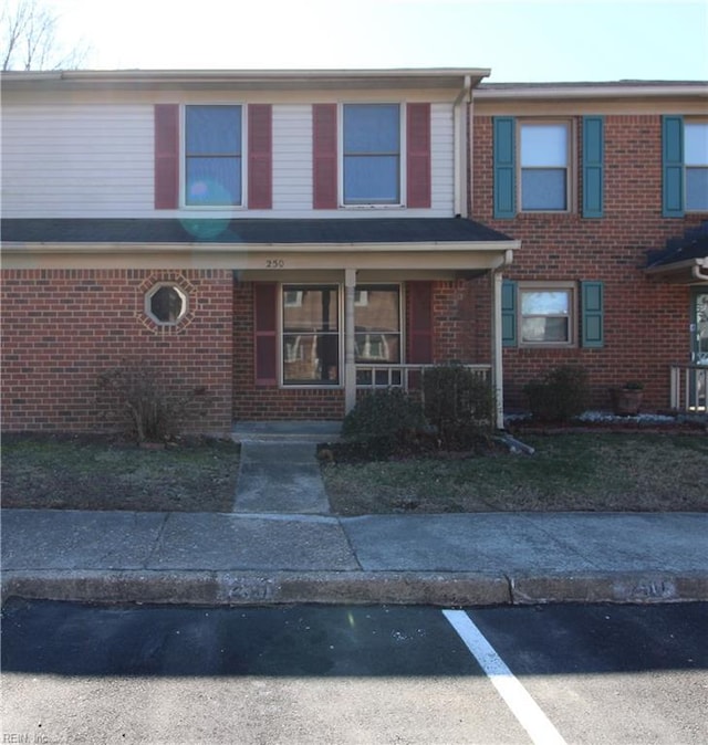 view of front of house with covered porch, uncovered parking, and brick siding