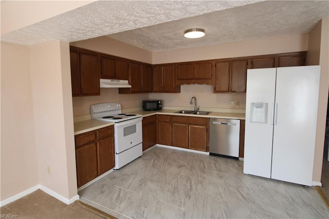 kitchen featuring white appliances, under cabinet range hood, light countertops, and a sink